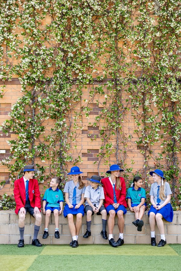 group of students of different ages sitting on a wall